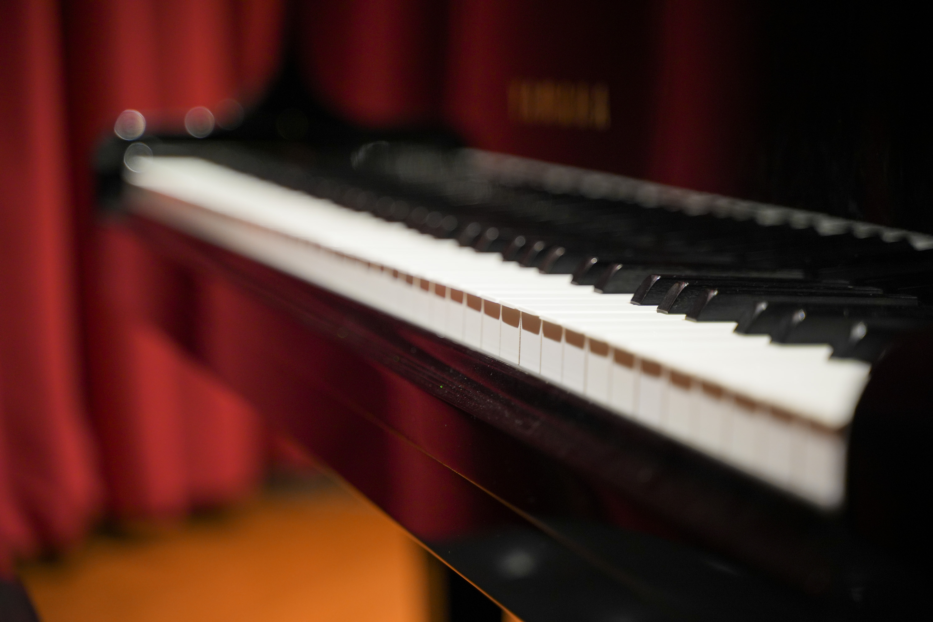 ピアノの寄り、赤いカーテンを背に