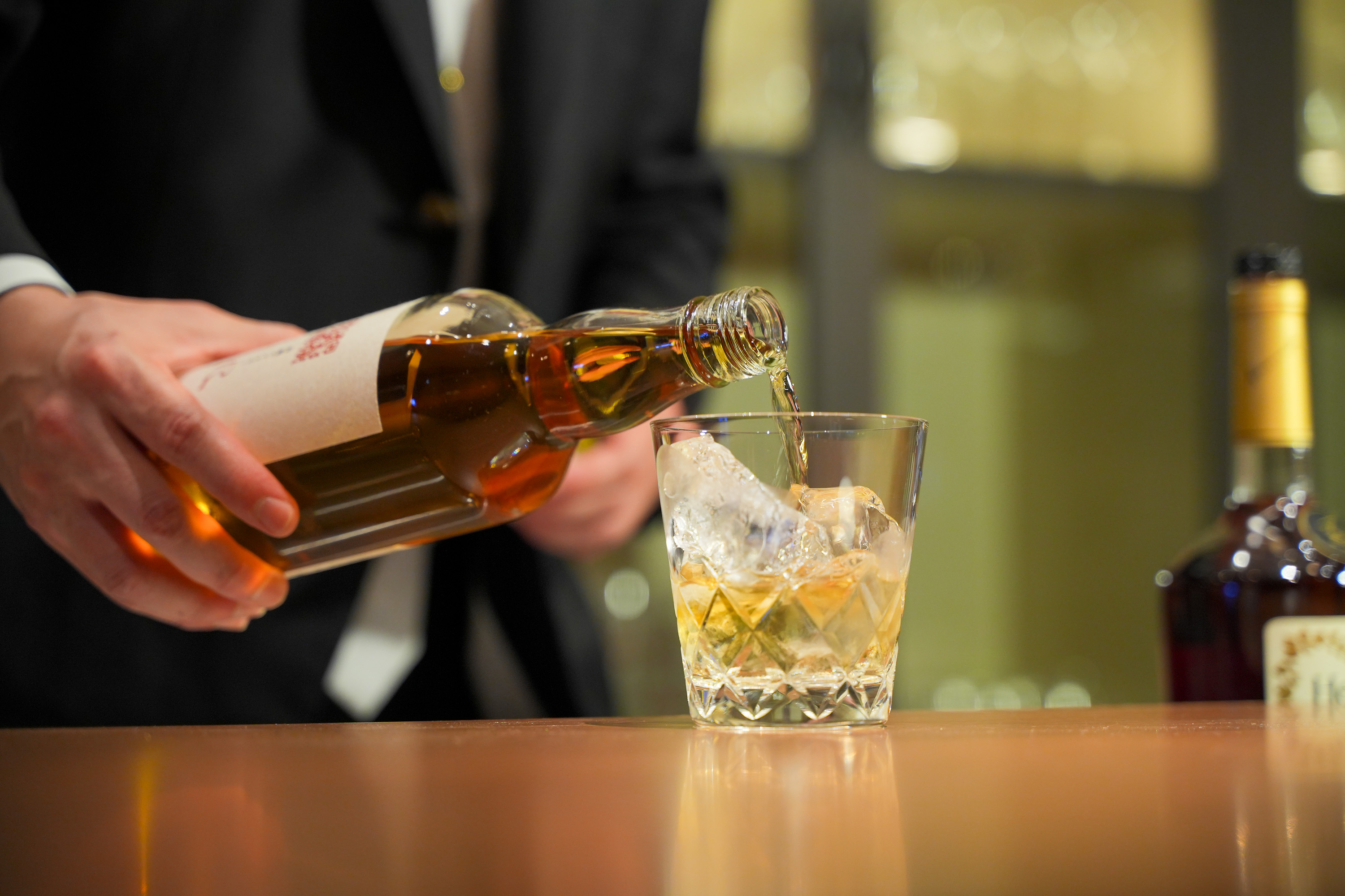ロックグラスにウイスキーを注ぐ手元