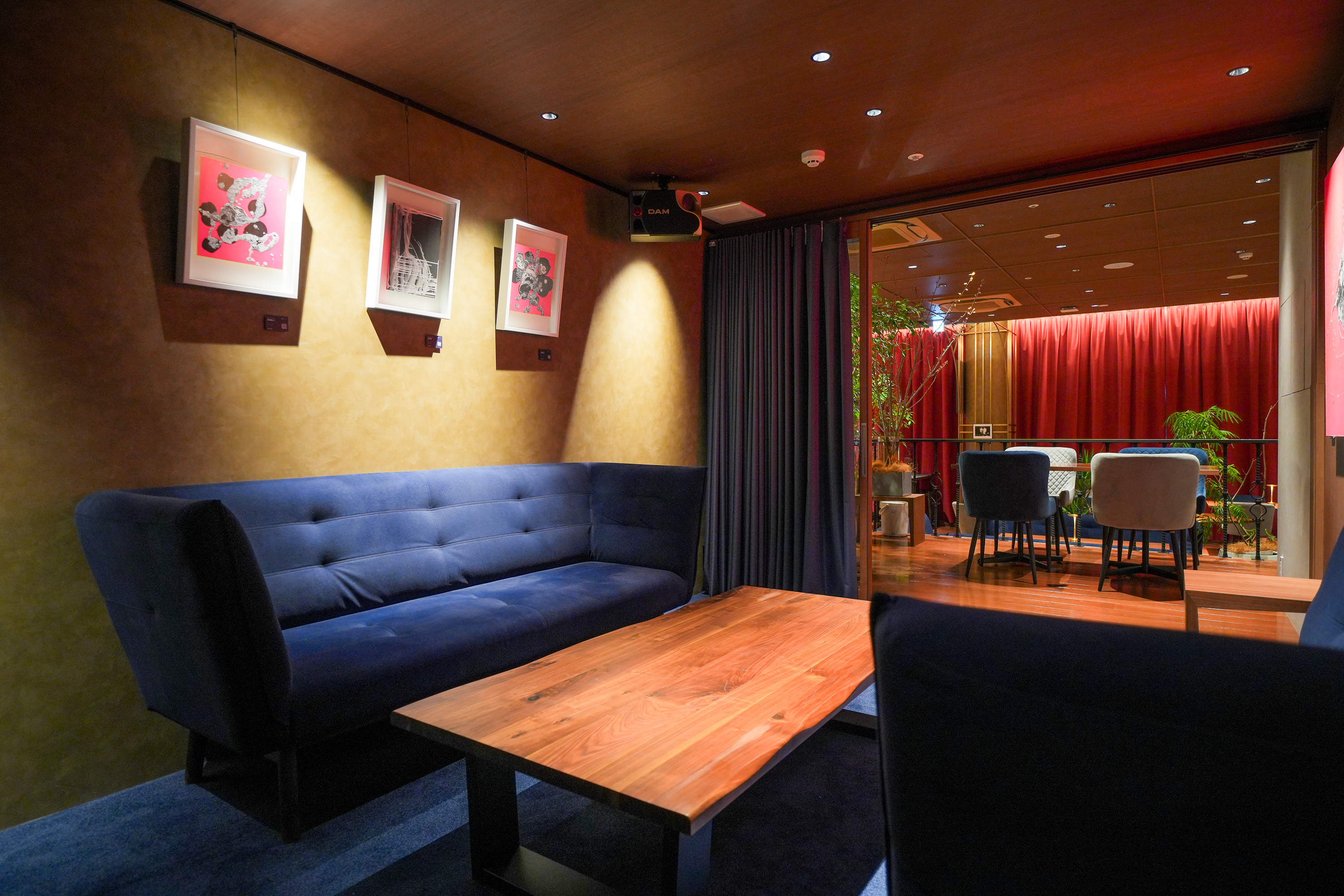 個室、絵画とブルーソファ、奥に深紅のカーテン